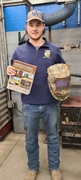 Picture of Jacob Costello with his textbook and welding helmet.